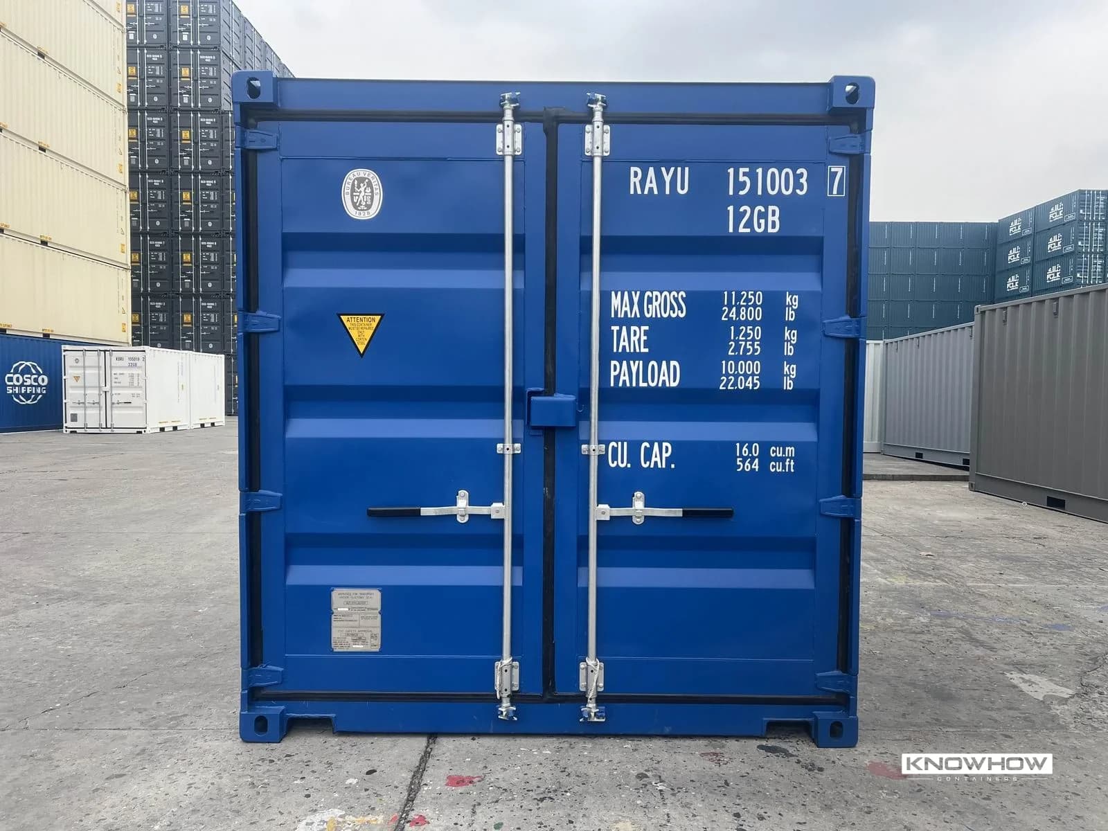 Blue 10ft dry van container door end view showing locking bars, hinges, and CSC plate with weight markings in a depot yard.